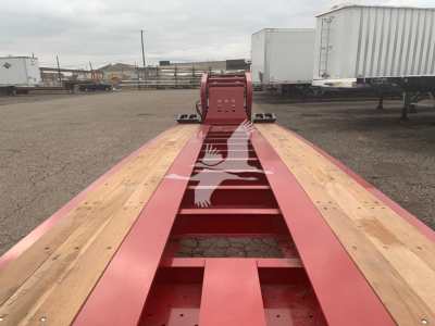 Long red Fontaine 55Lcc lowboy trailer deck with wooden planks and center beam, front attachment points visible.