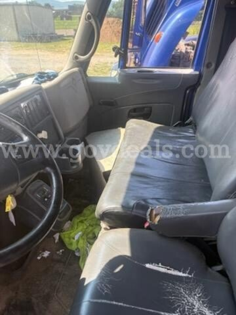 Interior of a used 2011 International 4400 cab showing driver seat and dashboard with wear on seat edges.