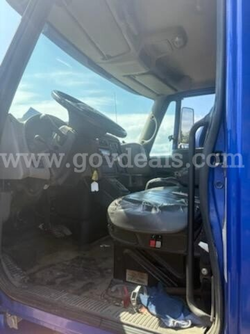 Interior cab view of a blue 2011 International 4400, front seats and steering wheel visible through open door, gear shifter and dashboard details present.