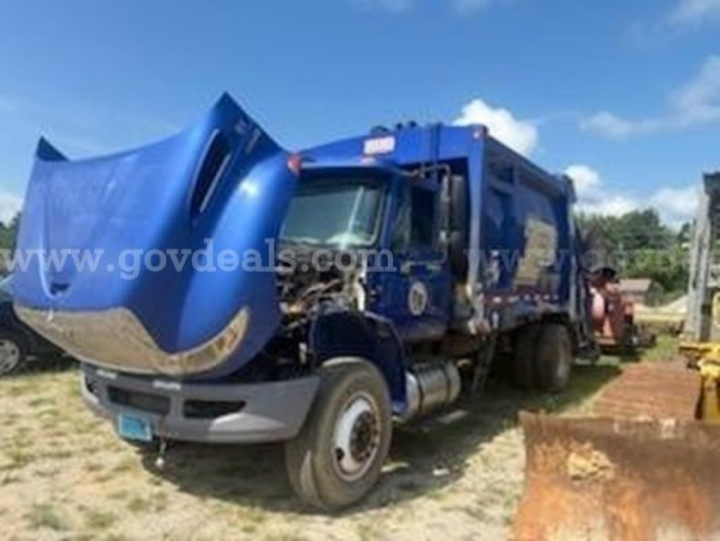 Truck front hood open with blue garbage truck body; side shows white text watermark; no clear close-up of labels or specs visible.