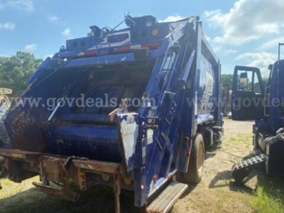Rear view of a blue 2011 International 4400 refuse truck with compactor, side steps, and rear hopper.