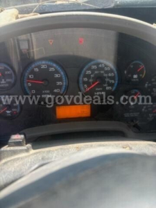 Dashboard of a truck showing speedometer and gauges with a small orange digital display; some warning lights illuminated.