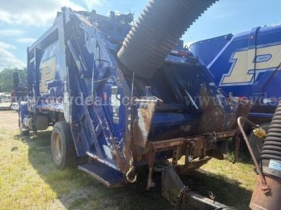 Truck body side view showing large blue international 4400 refuse truck with hopper and chute. Visible text includes 1? on blue background; no legible model or serial text.