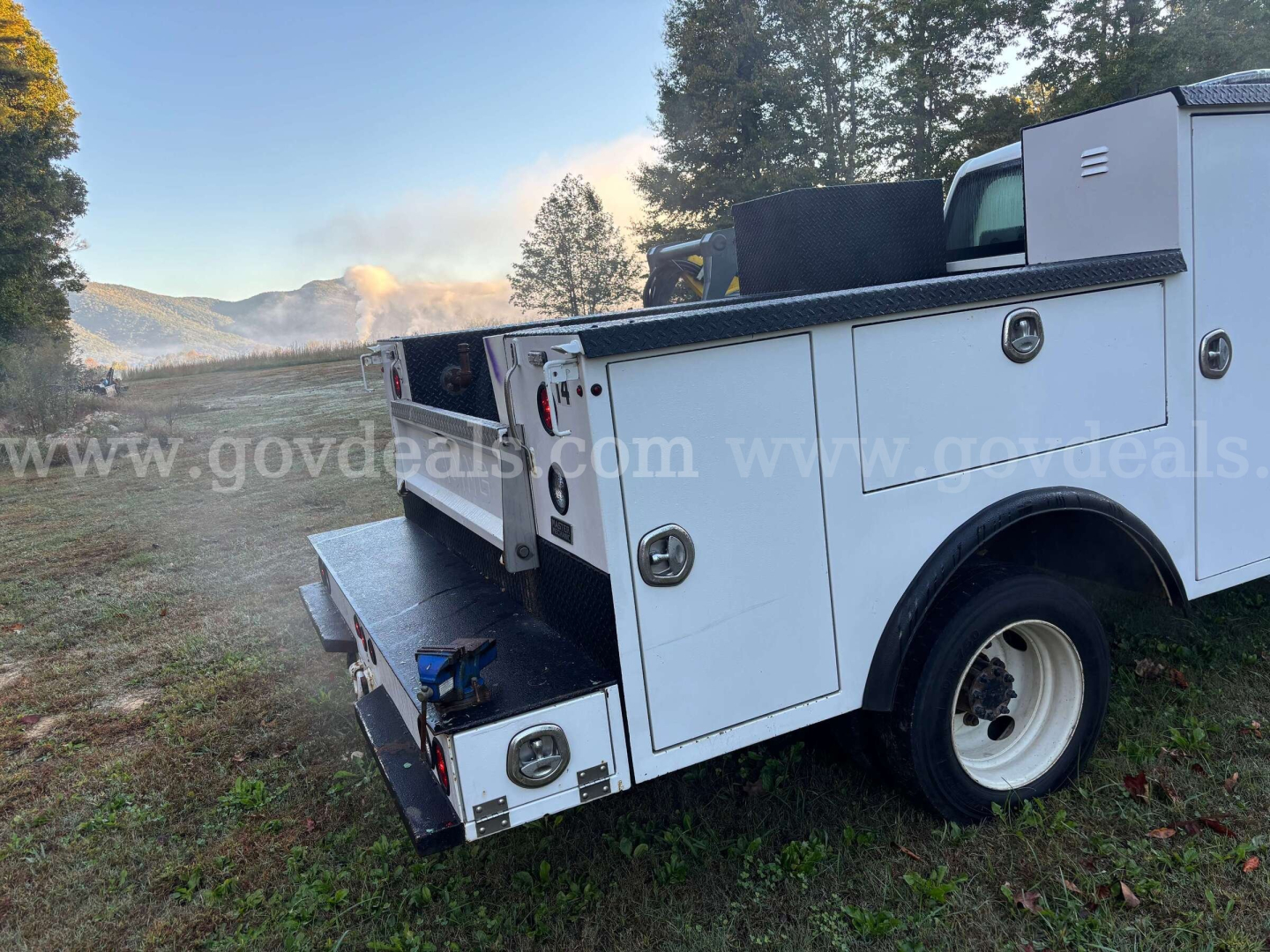Rear quarter view of a white service/utility truck bed with compartments and a towing hook, tag shows 2020 International CV515 equipment body.