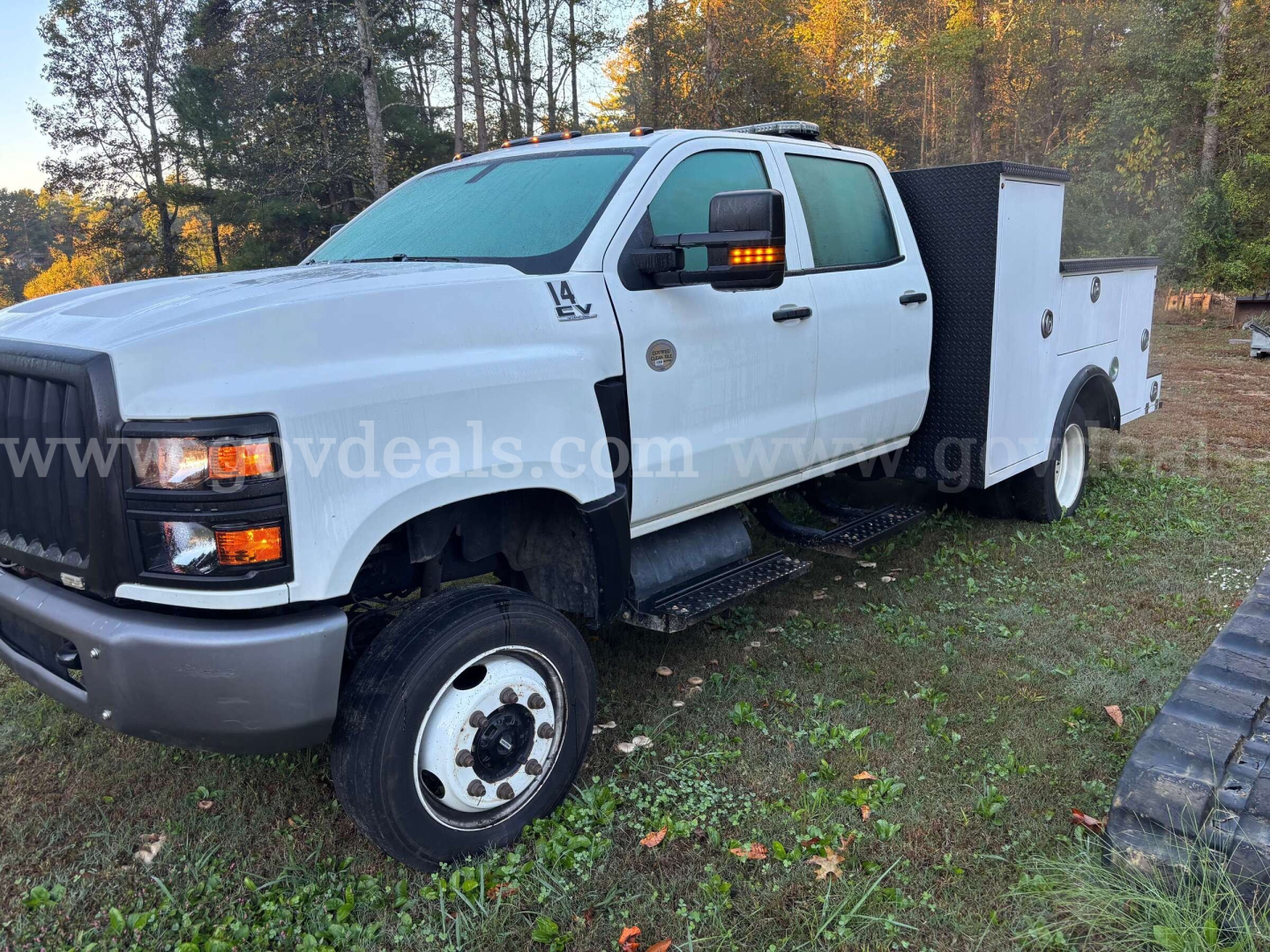 White 2020 International CV515 service/utility truck with utility toolbox, dual rear wheels, and gooseneck hitch visible; front grille and headlights clear.