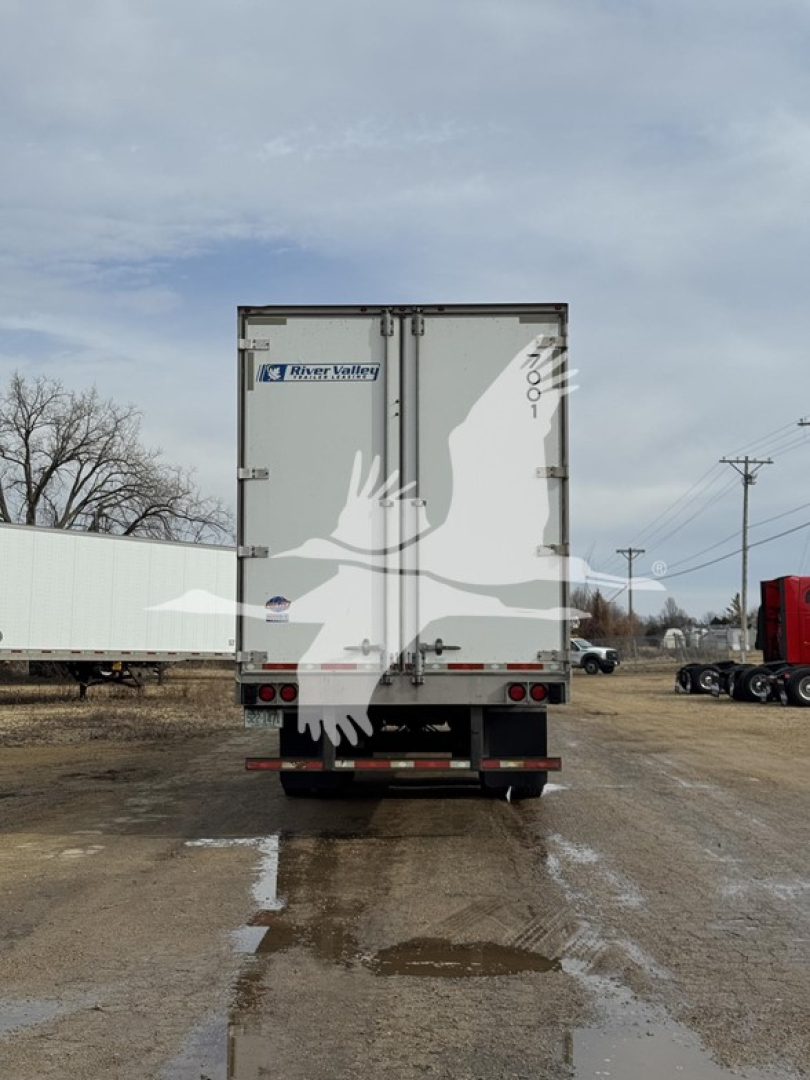 Rear view of a 2017 Utility dry van trailer showing two doors with Rivian stickers and taillights, on a muddy lot.