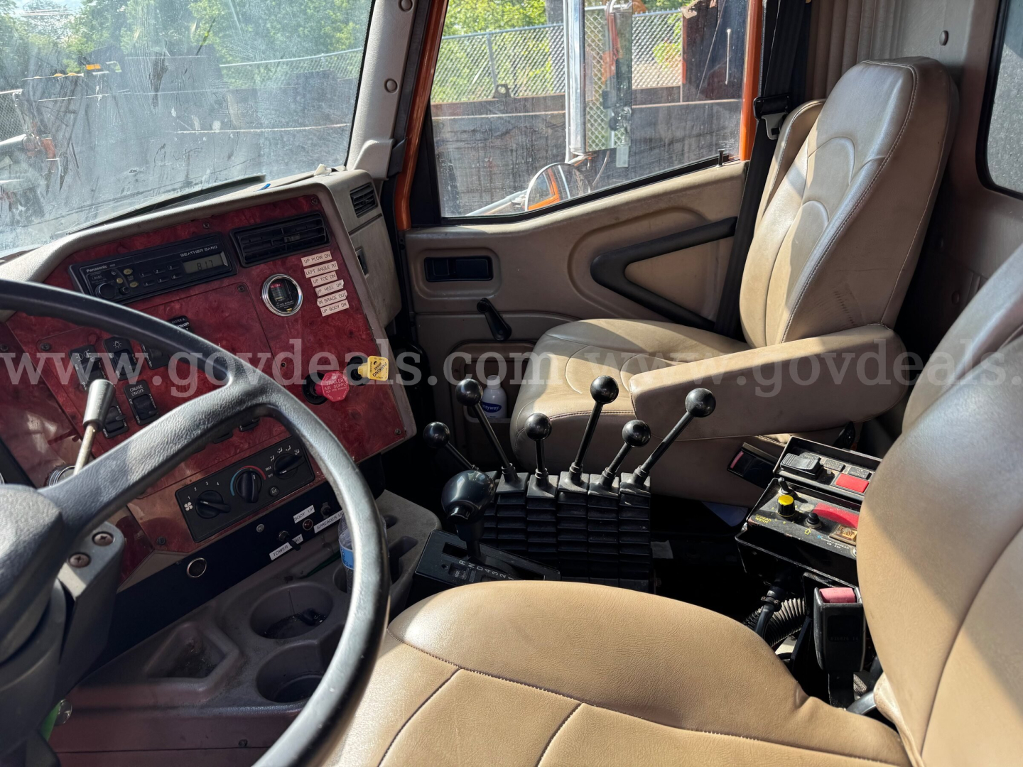 Truck cab interior showing steering wheel, gear shifters, and beige seats in a 2004 International 5600i dump truck.