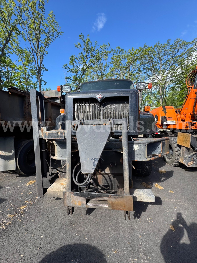 Front view of a 2004 International 5600i dump truck showing front grille, bumper, and mounting hitch with hydraulic components.