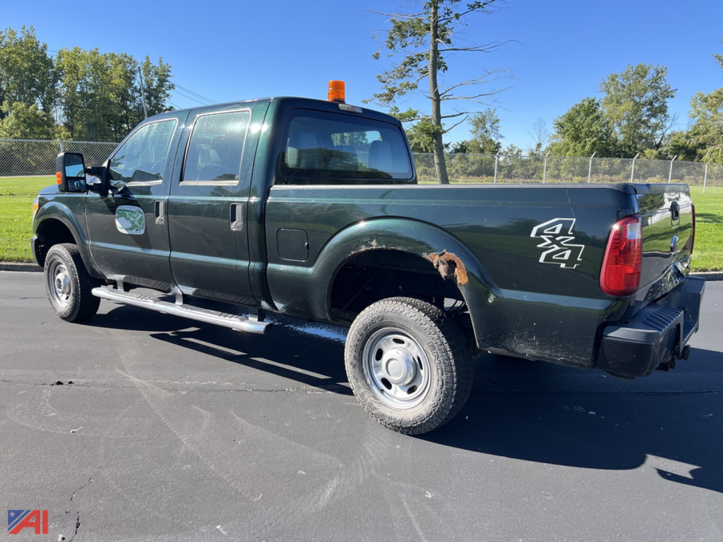 Green 2013 Ford F-350 Super Duty pickup truck with single rear wheel, orange cab marker light, Dually? actually SRW? wheel visible. Side badge shows 4x4 and F-350 logo on rear quarter. No visible text on windshield. Vehicle body has some ru