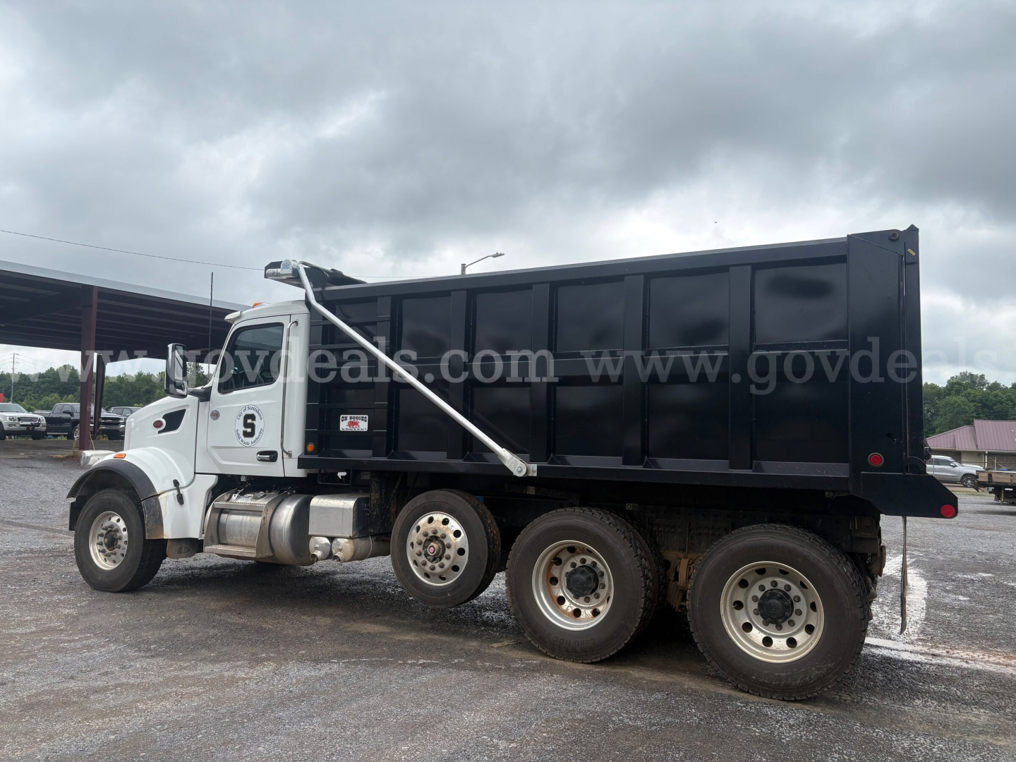 Dump truck 2025 Peterbilt 377 side view showing dump bed and dual rear axles.
