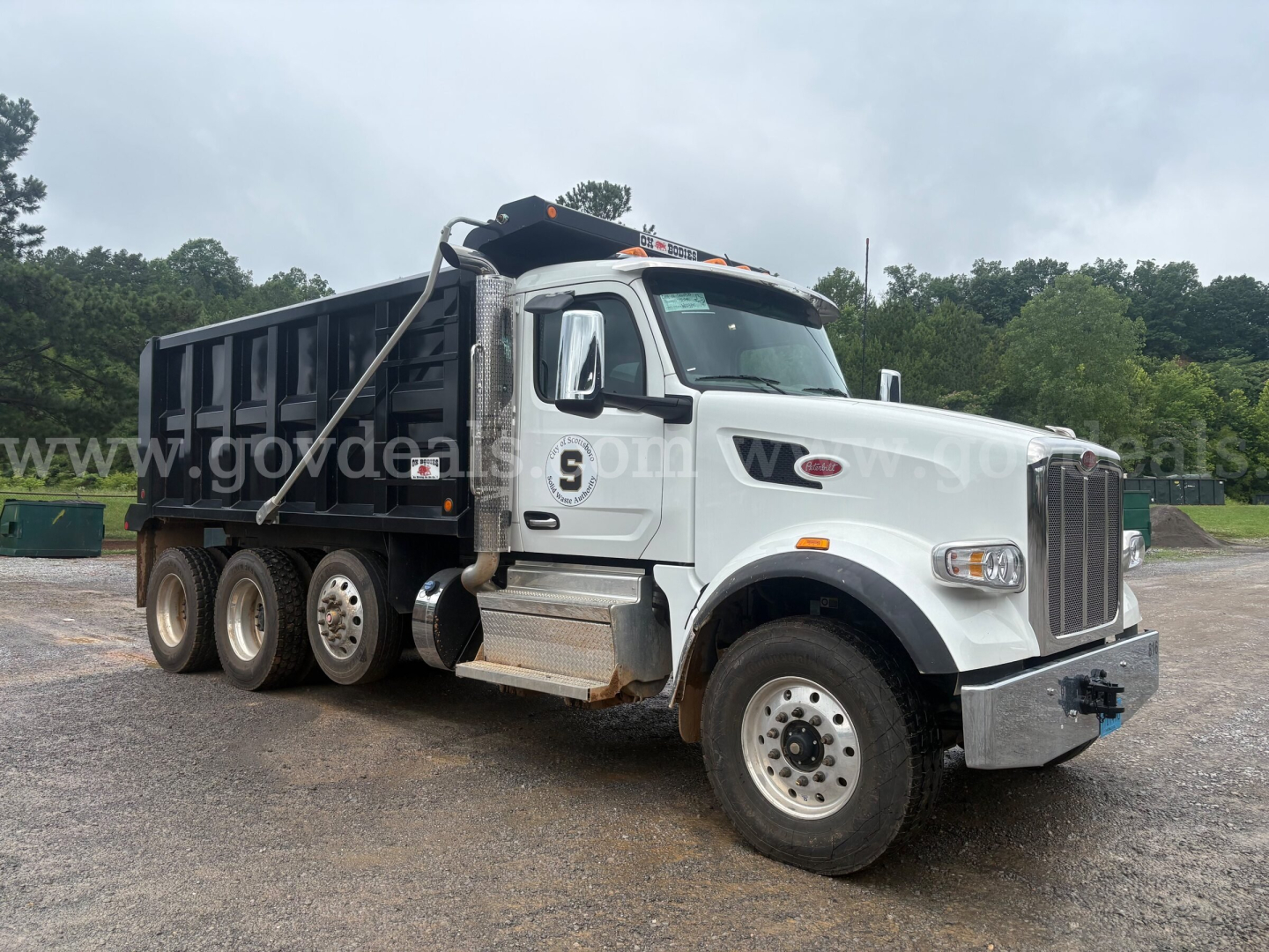 Peterbilt 377 dump truck in service with white cab and black dump bed, side view showing front grille and dual rear axles.