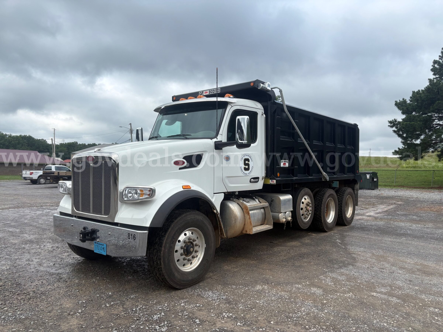 Peterbilt 377 dump truck in white with black dump bed, angled side view showing front grille, cab, and dual rear axles on gravel lot.
