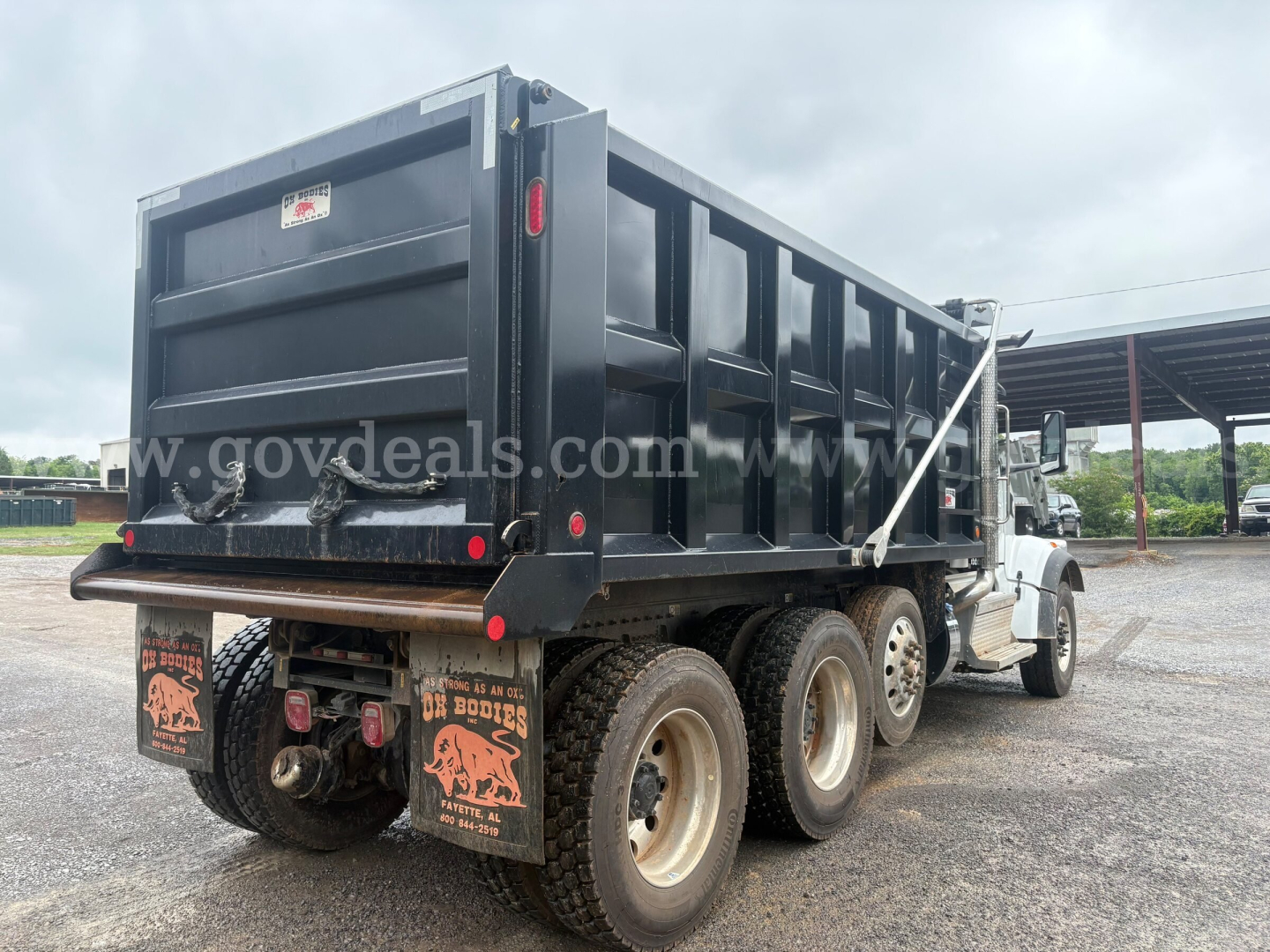 Peterbilt dump truck rear and side showing black dump bed and dual rear axles.