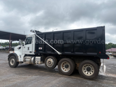 Dump truck 2025 Peterbilt 377 side view showing dump bed and dual rear axles.