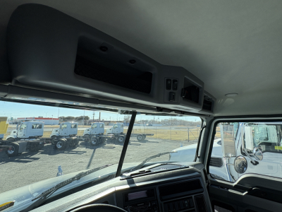Cab interior of a 2027 Mack GR64B truck showing dashboard and overhead compartment, with windshield and side mirrors visible