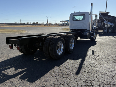 Mack GR64B chassis side view showing bare frame and rear tandem axles with white cab in background.