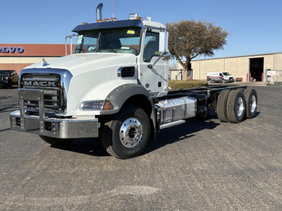 Mack GR64B truck front-left side with chrome bumper guard and dual rear axles, white cab, fuel tanks, and winch truck configuration.