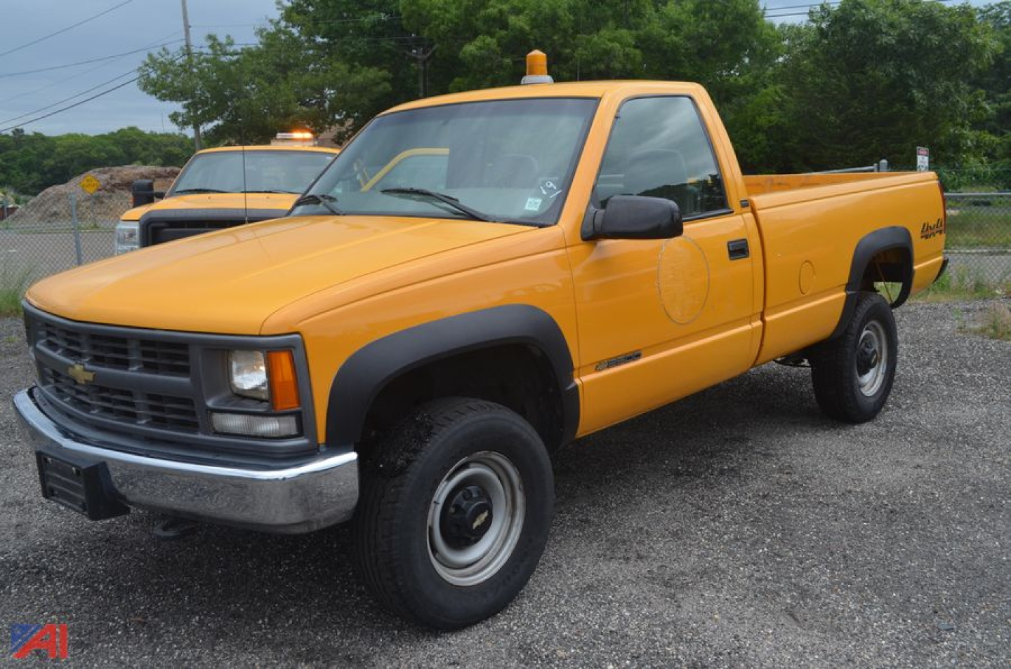 Chevrolet C/K 2500 series pickup truck in orange, front three-quarter view, 1997 model, single cab with utility bed and amber warning lights