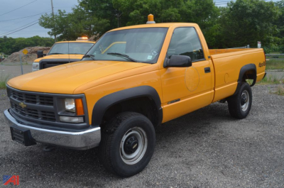 Chevrolet C/K 2500 series pickup truck in orange, front three-quarter view, 1997 model, single cab with utility bed and amber warning lights