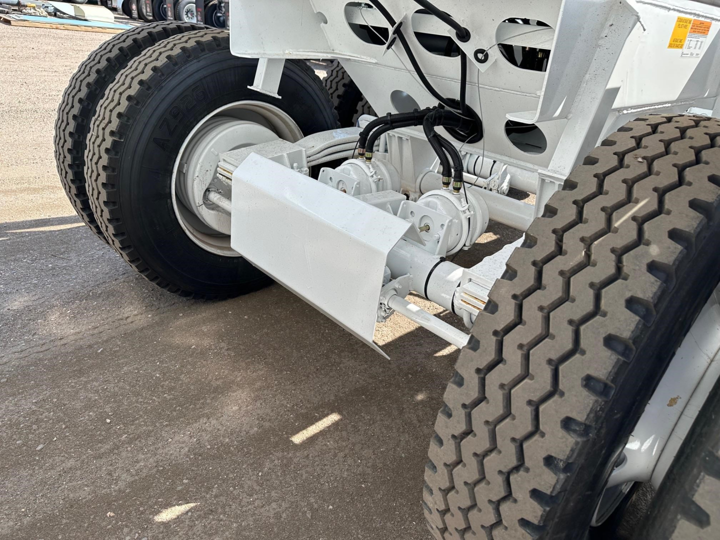Bottom dump trailer rear drivetrain showing tandem axle assembly with hydraulic actuated lifting mechanism and large dual tires.