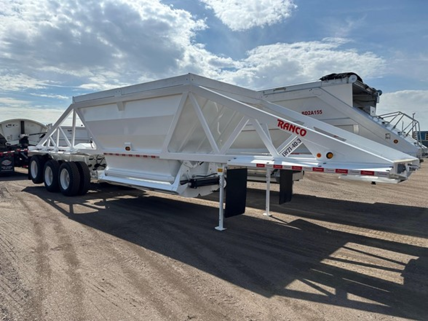 Ranco Tri Axle Bottom Dump trailer showing white body and frame with red RANCO logo and parked on lot.
