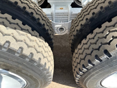 Bottom area of a 2026 Ranco Tri Axle Bottom Dump trailer showing dual rear dual tires and the hitch connection between axles.