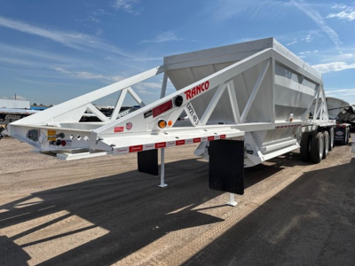 Ranco Tri Axle Bottom Dump trailer showing hydraulic cylinder and front hitch area with reflective tape and support legs.