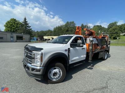 Truck-mounted drill rig on a Ford F-600 chassis with an orange mounted drilling unit, side view showing front grille, wheels, and rig equipment.