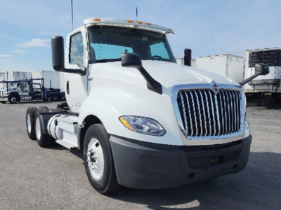 Truck cab showing International LT625 with chrome grille, white exterior, black bumper, two side mirrors, and heavy-duty dual rear axles.