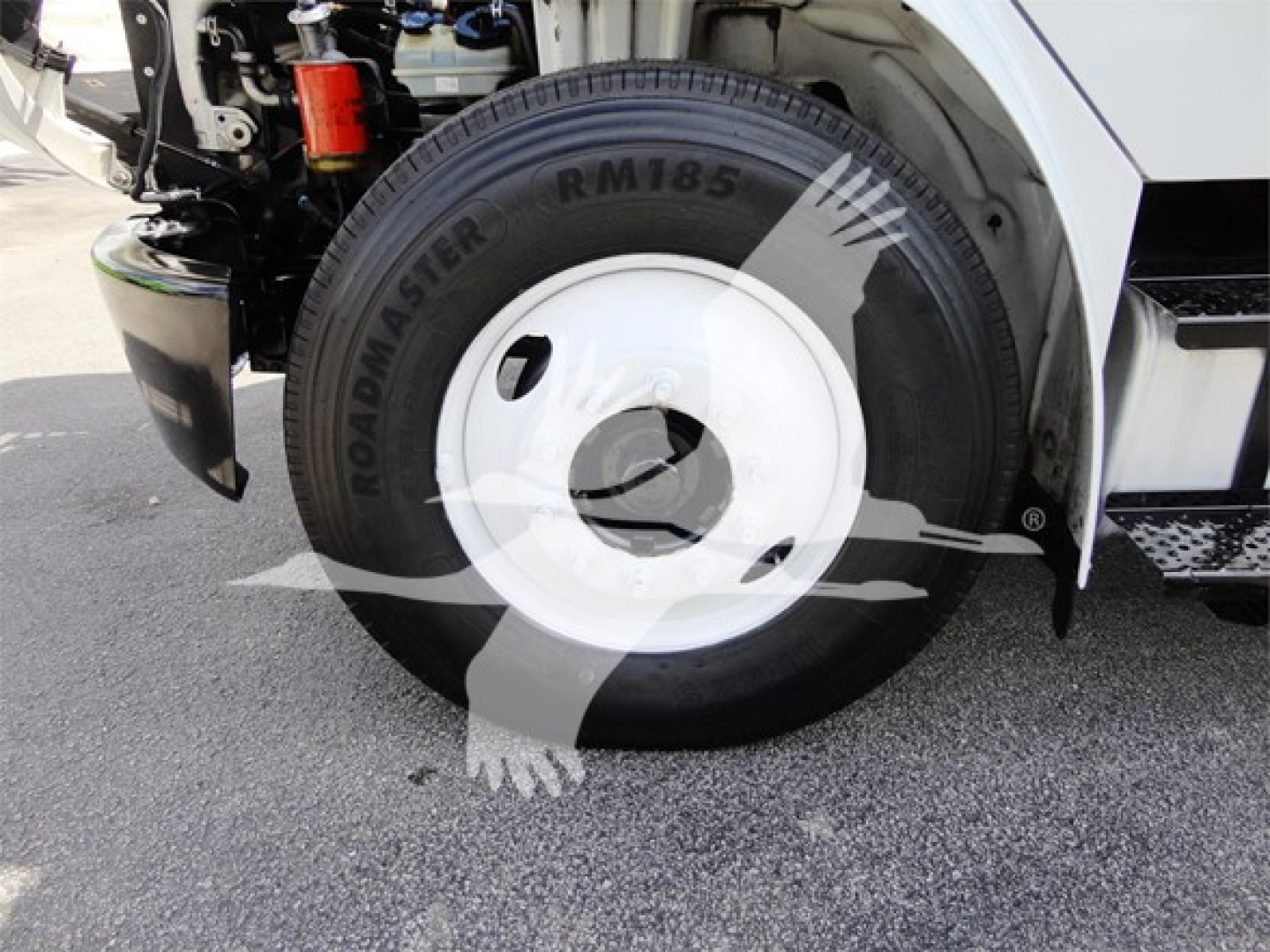 Truck wheel and front fender of a 2014 Freightliner M2 106 showing roadmaster RM185 tire and white hubcap.