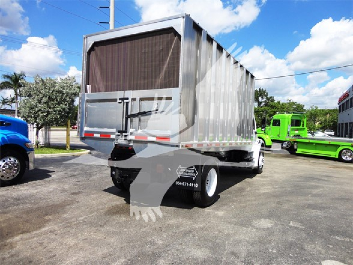 Freightliner M2 106 chipper truck rear view showing dump bed and dual rear wheels in a dealership lot.