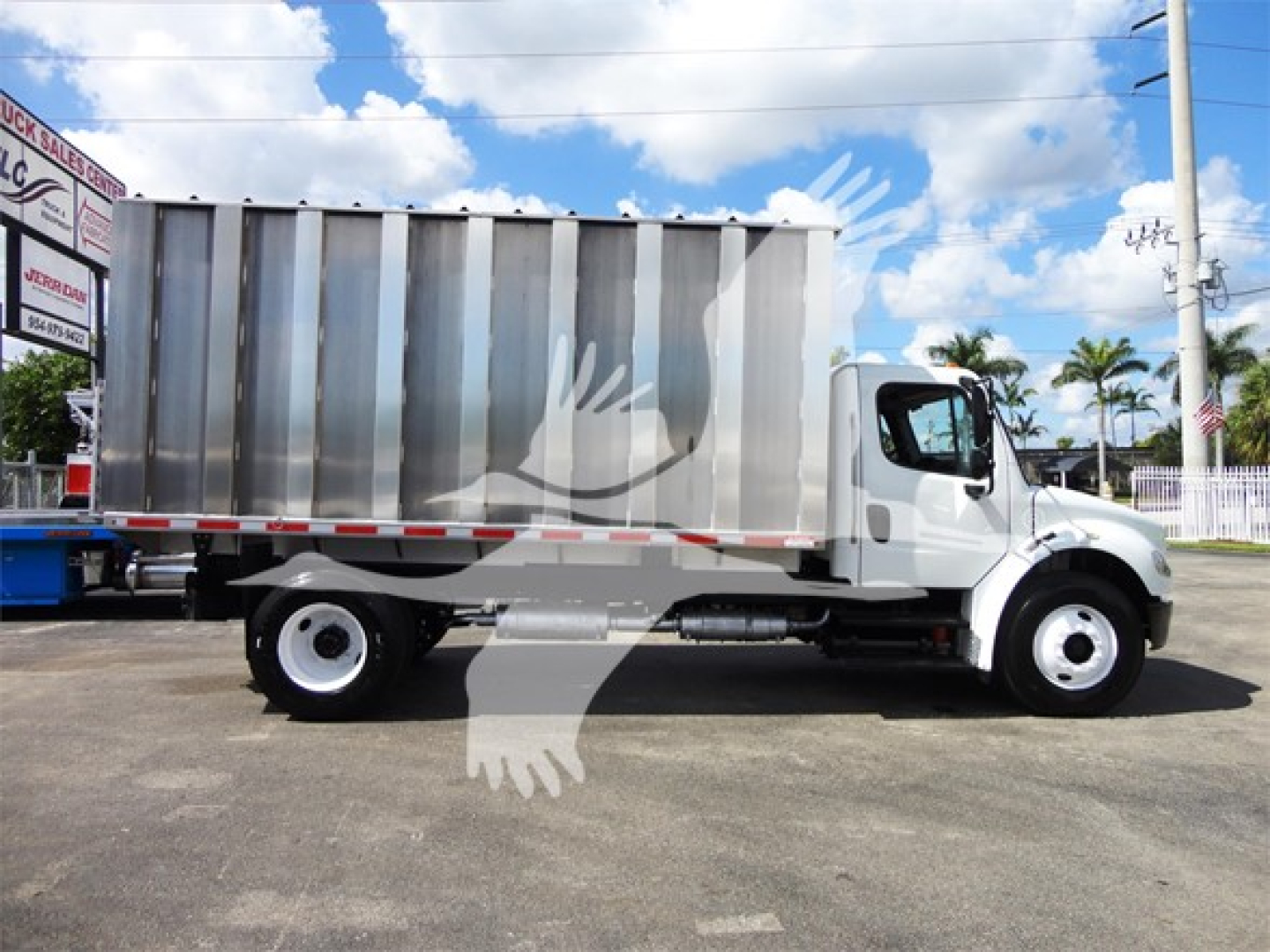 Truck side view showing a white 2014 Freightliner M2 106 with a silver dump bed in a dealership lot.