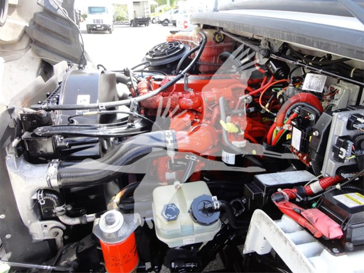 Freightliner M2 106 engine bay with red engine components, hoses, and coolant reservoir visible.