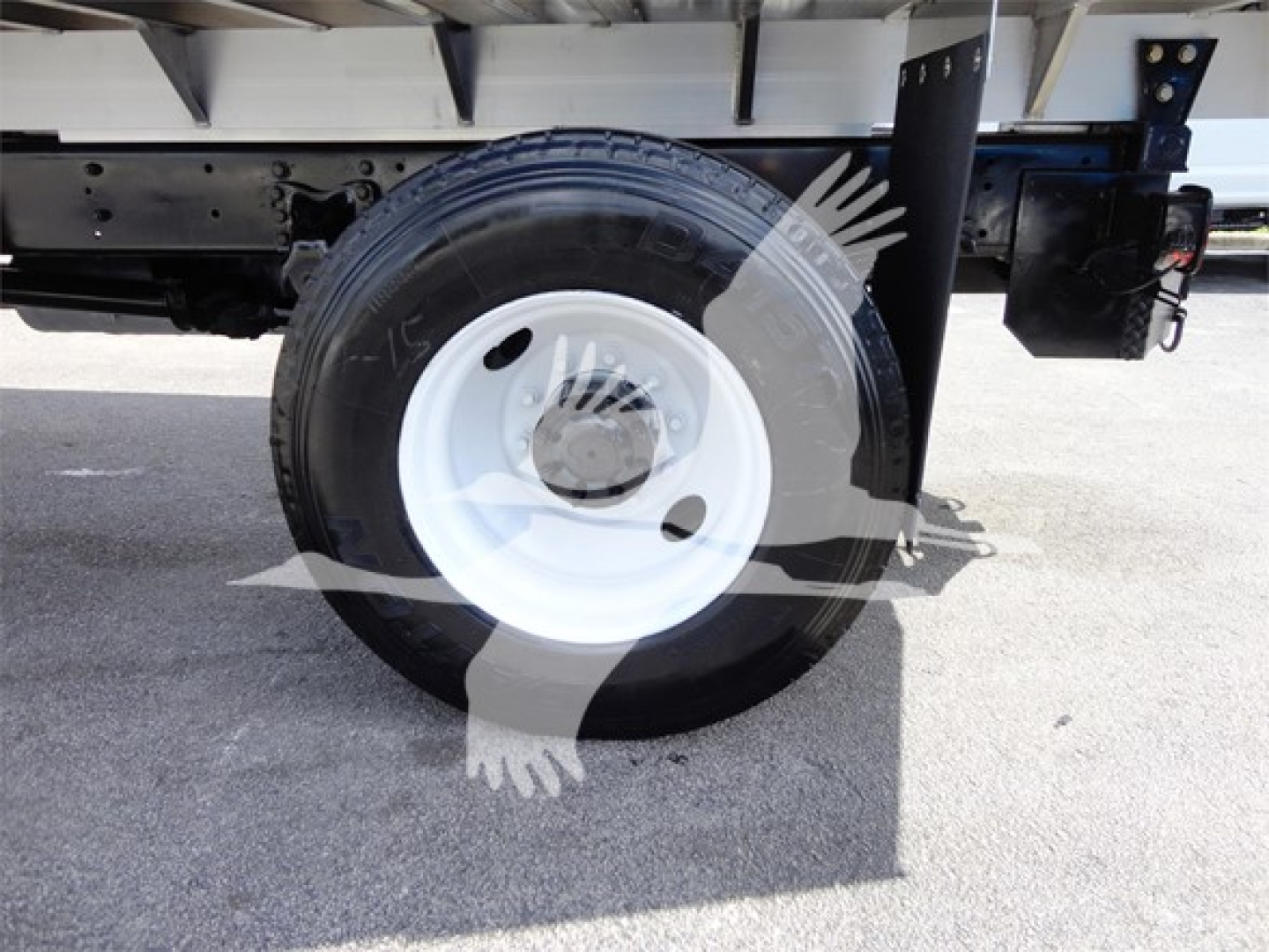 Truck wheel and undercarriage view showing a white steel wheel with black tire and surrounding chassis components.