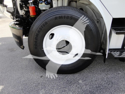 Truck wheel and front fender of a 2014 Freightliner M2 106 showing roadmaster RM185 tire and white hubcap.