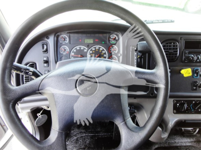 Cab interior of a Freightliner M2 106 truck showing steering wheel dashboard and controls.