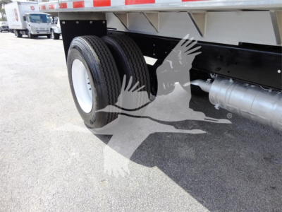 Freightliner M2 106 chassis with dual rear wheels and side fuel tank. Visible text on the truck includes VIN plate and stock number area, with a chipper category truck. The image shows the undercarriage and wheel assembly.