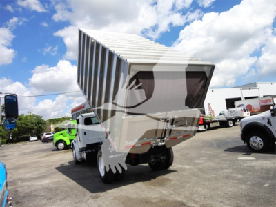 Freightliner M2 106 with a raised dump bed showing front cab and raised container in a dealership lot.