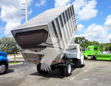 Freightliner M2 106 dump truck bed in raised position showing hydraulic components and chassis.