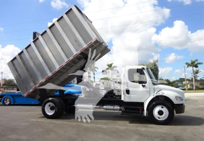 Freightliner M2 106 dump truck side view showing raised dumping bed and white cab.