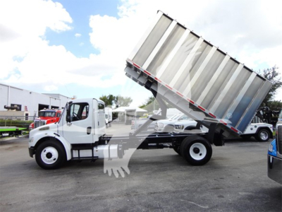 2014 Freightliner M2 106 truck with tilted dump bed in a dealership lot, side view showing cab and chassis