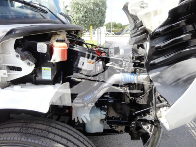 Freightliner M2 106 engine bay showing coolant reservoir, hydraulic lines, and exposed engine components.