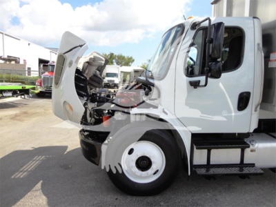 Truck engine bay of Freightliner M2 106 showing front hood open and cab side view.