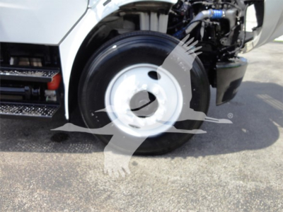 Front wheel well and engine bay of a Freightliner M2 106 truck showing front tire and partial chassis components.