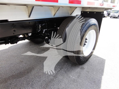 Freightliner M2 106 wheel and undercarriage view showing front wheel, suspension, and chassis with white rim; chipper truck body visible above.