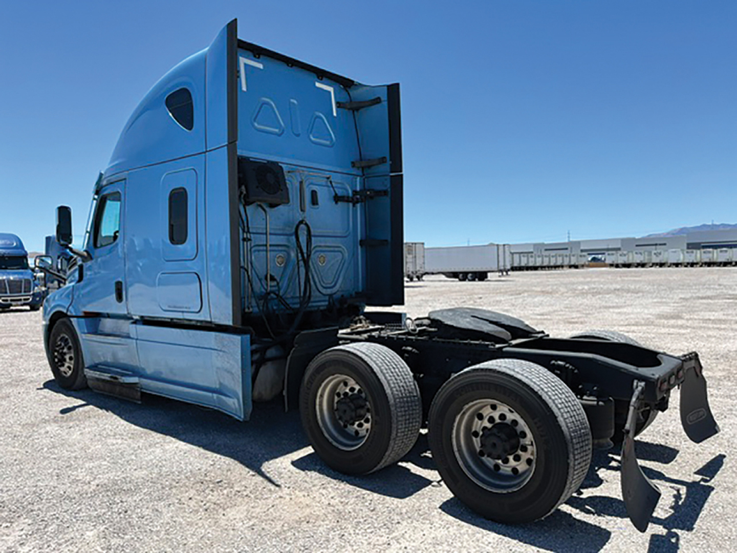 Freightliner Cascadia truck tractor cab and rear chassis with fifth wheel removed, side view showing rear wheels and blue cab.