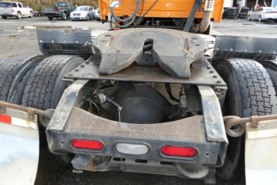 Rear view of a Volvo VNM truck chassis showing fifth wheel, dual rear axles, mud flaps, and dual taillights with dirt and wear.