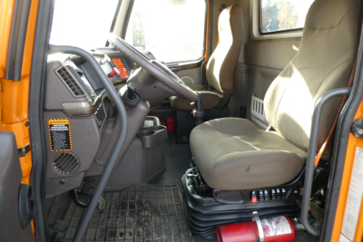 Truck cab interior showing steering wheel, driver's seat, and dashboard with floor mat in Volvo VNM42T daycab.