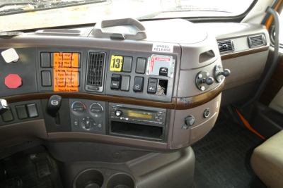 Volvo VNM42T truck cab interior dashboard with orange warning labels, controls, and stereo unit visible.