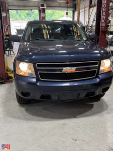 Front view of a blue 2008 Chevrolet Avalanche pickup truck in a showroom or service bay, showing the Chevrolet bowtie grille and headlights.